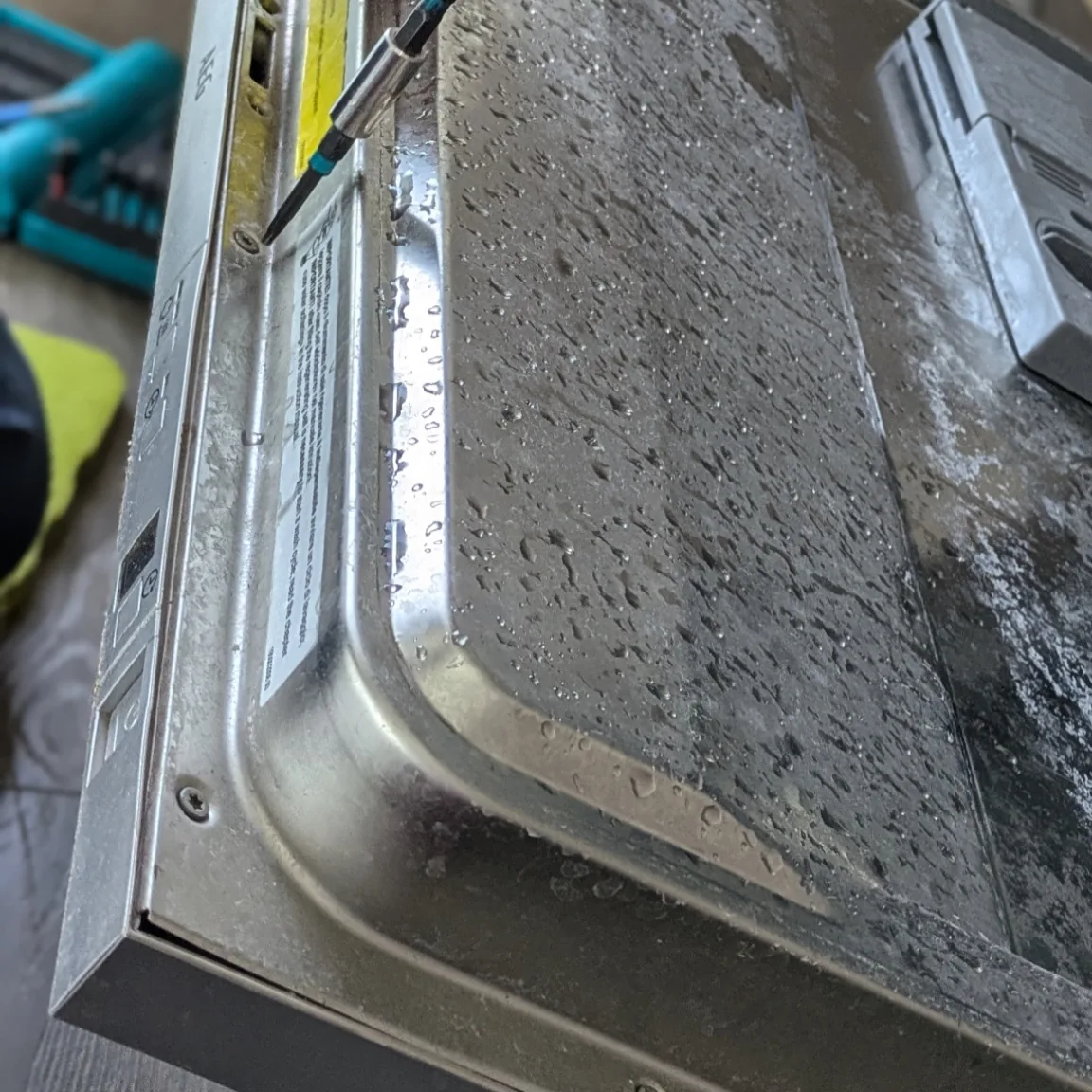 Technician diagnosing a dishwasher with a multimeter